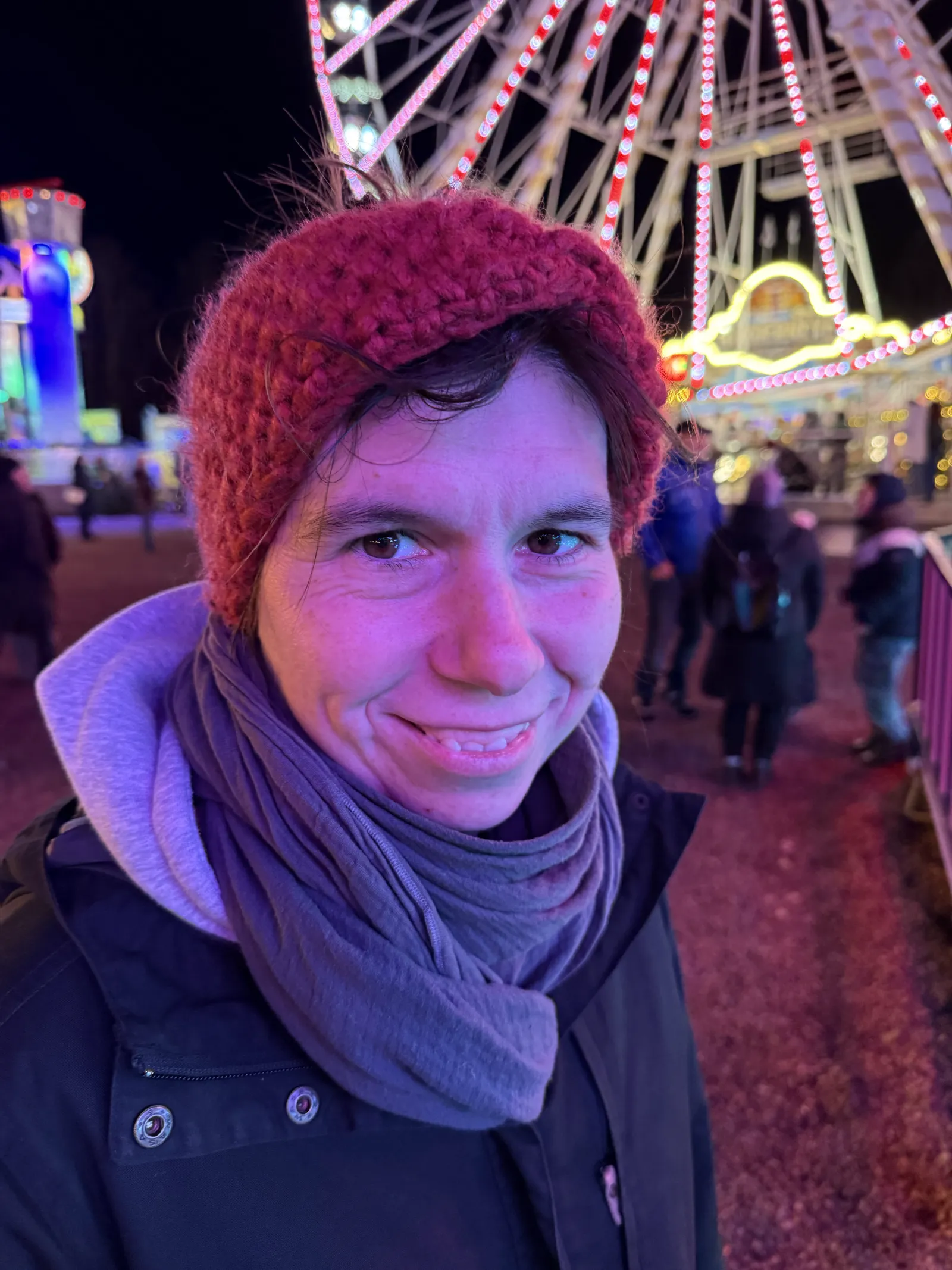 Porträt von Jule vor den Lichtern eines Riesenrads am Abend, entspanntes Lächeln.